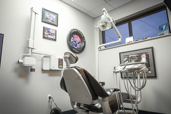 The image shows an interior view of a dental office, featuring a dental chair with a patient s headrest and a large mirror above it.