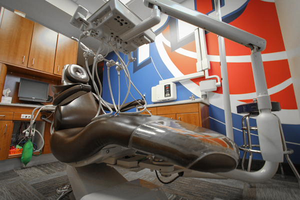 A modern dental chair with a digital display and various controls, set within a clean, professional dental office environment.