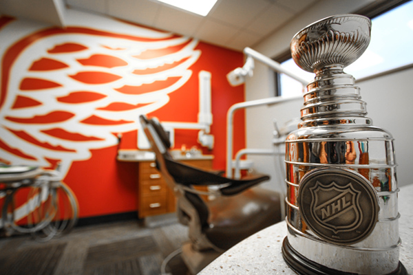 A trophy with a hockey team's logo on it, placed on a dental chair in an office decorated with sports memorabilia.