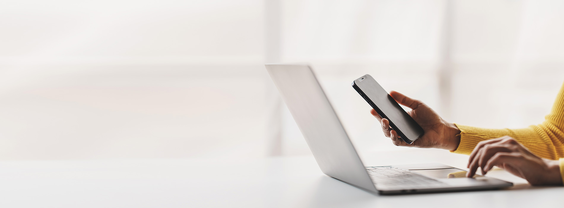 A person using a laptop while seated at a desk, with a blurred background.