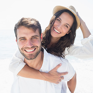 A man and a woman sharing a joyful moment on the beach, with the man holding the woman close to him.