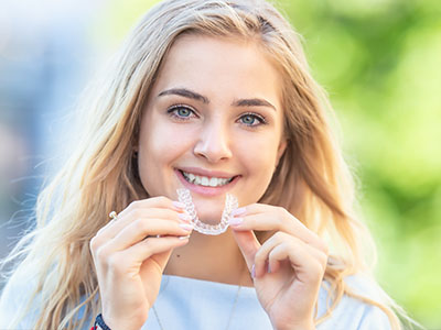 The image shows a smiling woman holding a toothbrush with a smile on it, which is likely meant to be humorous or illustrative of oral hygiene.