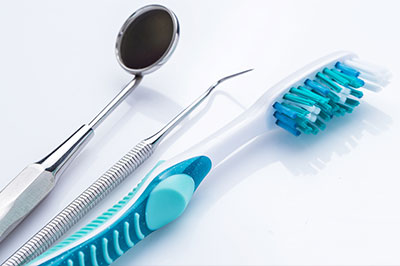 Dental tools including a toothbrush and tweezers on a white surface.