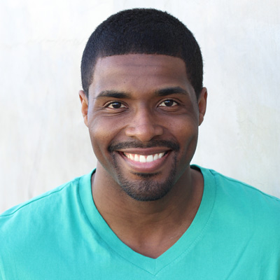 The image shows an older couple, a man and a woman, smiling at the camera. They are embracing each other while sitting close together outdoors during what appears to be sunset or early evening, as suggested by the warm lighting and the relaxed atmosphere.