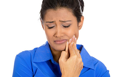 Woman with hand on face, appearing to be in distress or discomfort.