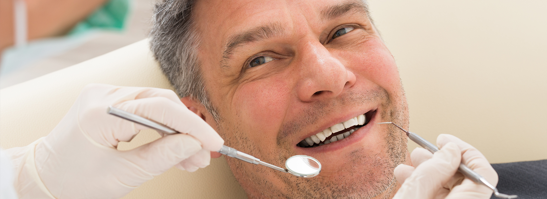 A man is sitting in a dental chair, smiling at the camera, with his mouth open as if he s undergoing a dental procedure.