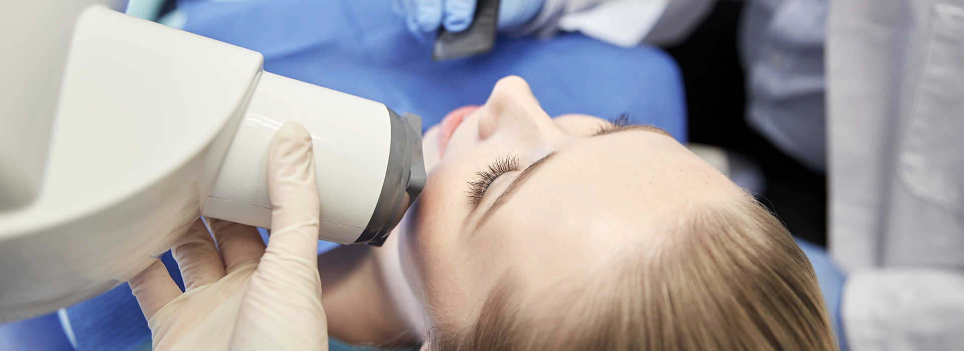 A person is receiving a dental implant procedure, with a dentist using a microscope to guide the placement of the implant.