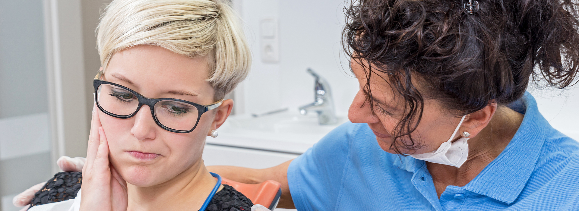 A photograph of a woman with glasses and a man in a blue shirt with a stethoscope around his neck, both in a dental office setting.