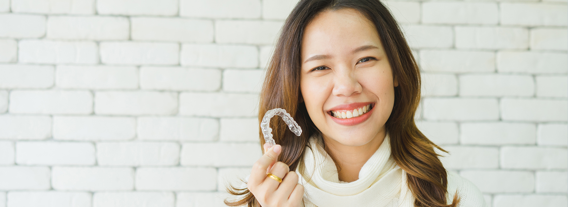 A woman is smiling and holding a ring in front of her.