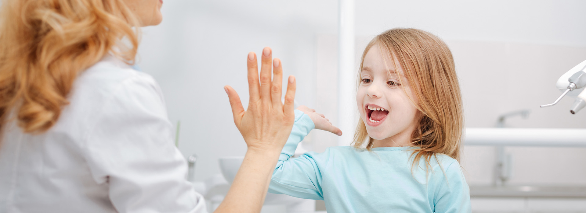 A woman and a child in a dental office, with the woman showing something to the child.