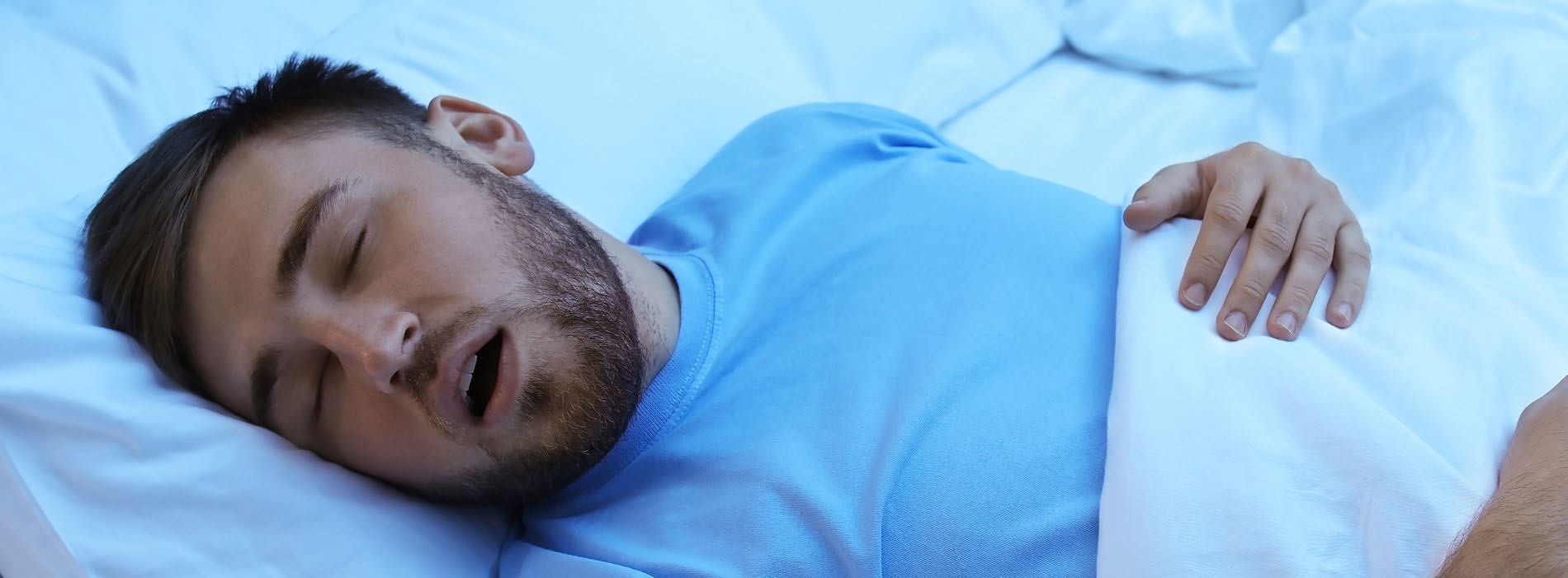 The image shows a man lying in bed with his eyes closed, appearing to be asleep.