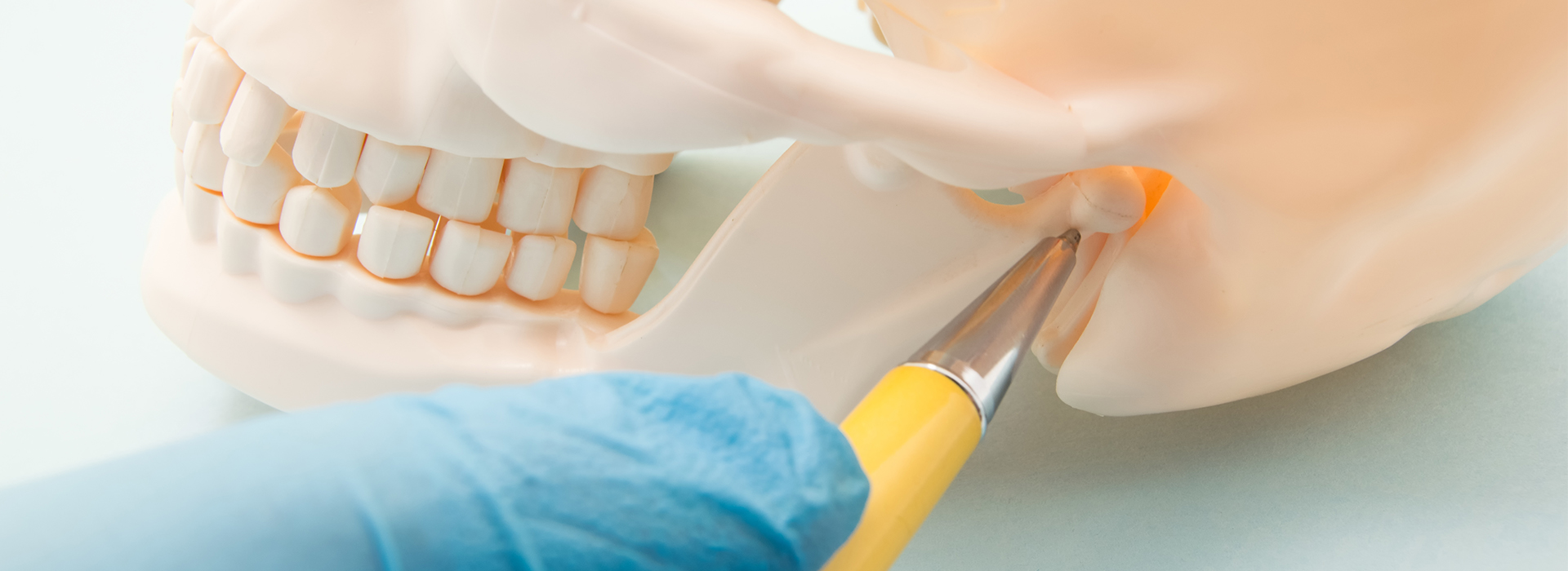 The image shows a close-up of a human skull with a surgical tool being used on it, likely in a dental or medical setting.