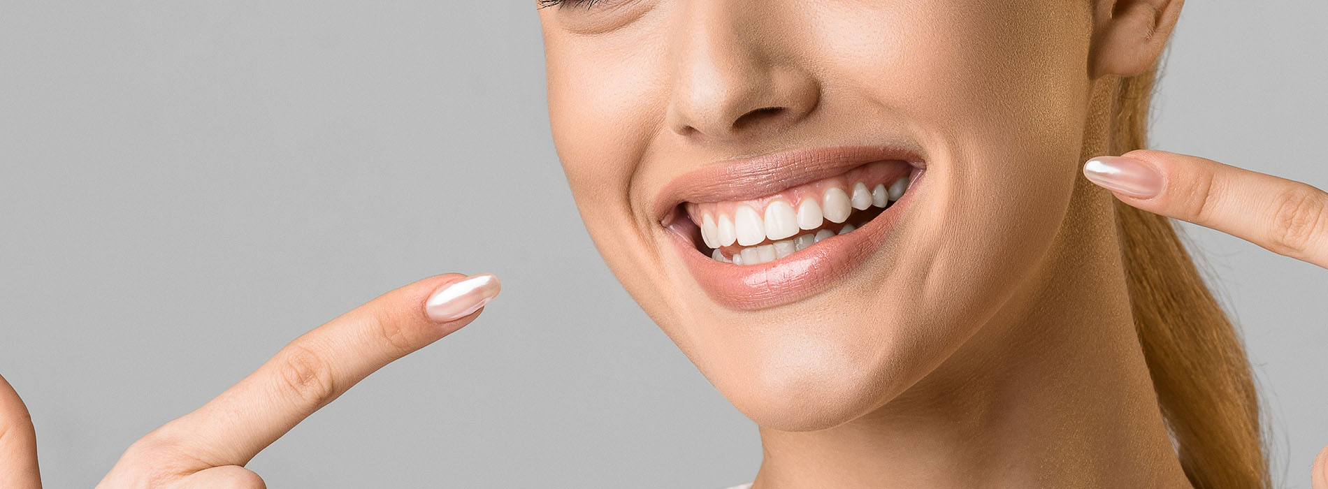 A smiling woman with a pointed finger, set against a neutral background.