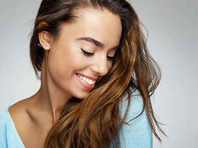 The image is a close-up portrait of a woman with long hair, smiling softly.