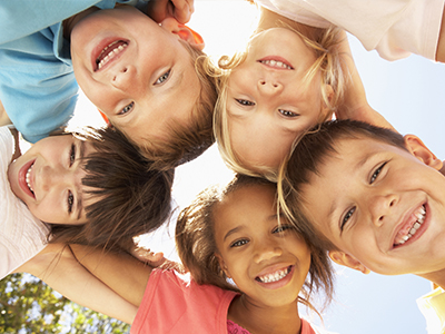 A group of children in a joyful pose, with one child standing upright in the center.