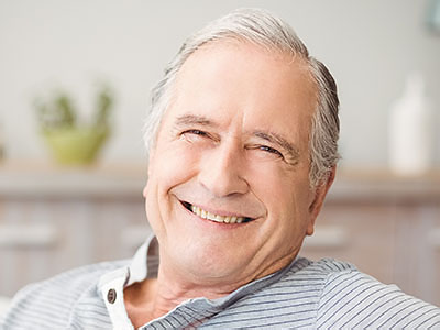 An elderly man with a smile, sitting in a relaxed posture.