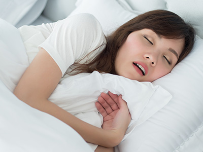 A woman is sleeping peacefully in a large bed with white sheets.