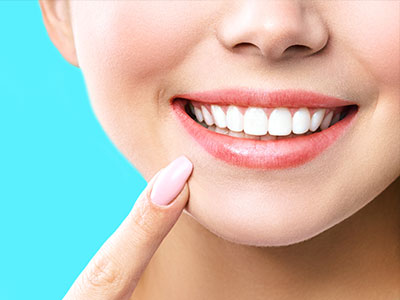 A close-up image of a person smiling, showcasing their teeth and lips against a blue background.